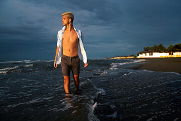 Stylish man relaxing at tropical beach during summer vacation. Carefree guy relaxing at sea.