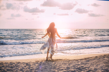 Silhouette of beautiful young happy woman tourist walks runs by coastline. girl admires beauty...