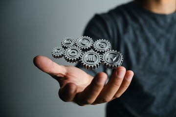 Silver gears with financial symbols held in open hand currency business