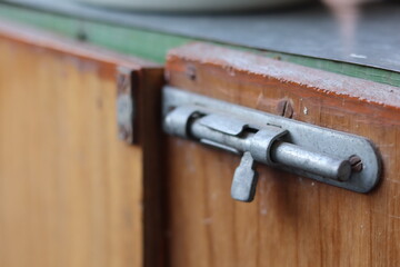 Metal latch on a wooden cabinet in a rustic kitchen at morning light creating a cozy atmosphere