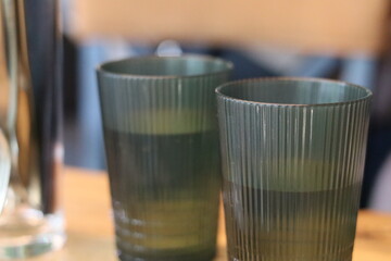 Glasses on a wooden table with softly colored water amidst a casual indoor setting