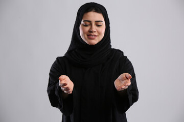 saudi arabian woman in hijaab standing offering help hands looking towards ground with a smile
