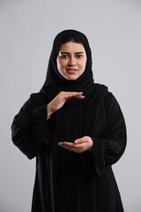 saudi arabian woman in hijaab standing offering help holding hands facing camera with a smile