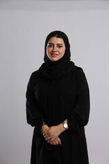saudi arabian woman in hijaab standing folded hands facing camera with innocent smile