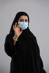 saudi arabian woman in hijaab mask on face standing with perfect sign