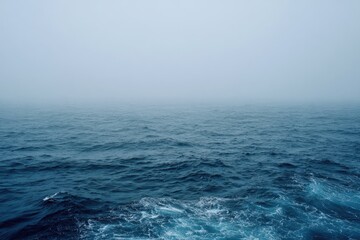 A misty, overcast day at sea.  Dark blue water with small waves stretches to a hazy horizon