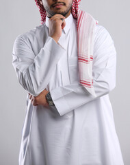 saudi arabian man in thob standing with hand to his chin