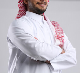 saudi arabian man in thob standing with hand folded and smiling  side angel