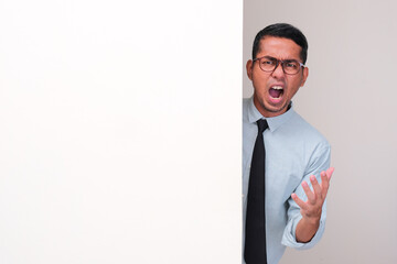 An employee peeking behind a wall showing frustration expression