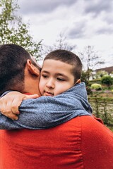 Close-up of a 6 year-old boy hugging his father. The image captures a tender family moment focused...