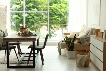 Wooden table, chairs, sofa and decor in dining room. Interior design
