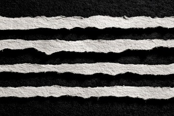 Four uneven, torn strips of light-grey paper lie horizontally against a dark, textured background, creating a stark contrast and rough texture