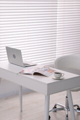 Open trendy magazine, laptop and coffee on white table indoors