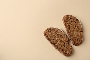 Pieces of fresh rye bread on beige background, top view. Space for text