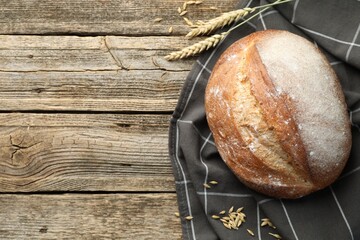 Loaf of fresh bread and spikes on wooden table, flat lay. Space for text