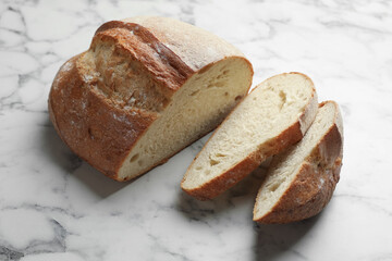 Pieces of fresh bread on white marble table, above view