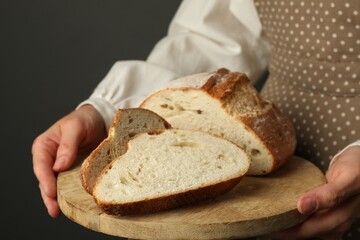 Woman with pieces of fresh bread on grey background, closeup