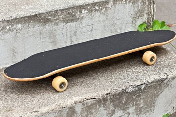A black deck skateboard rests on weathered concrete steps
