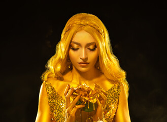 Real person art photo portrait fantasy woman queen holding in hands white rose flowers. gold color hair dress shines. Black studio. Blonde fairy princess girl golden paint skin beauty face make-up