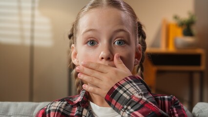 Portrait surprised little school girl child kid daughter preteen looking at camera at home sofa...