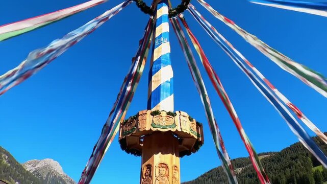 oktoberfest celebration in october in germany. symbolic shot of traditional bavarian maibaum, maypole. tall thin wooden pole colored in white and blue stripes, decorated with festive ribbons.