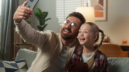 Caucasian happy family make selfie photo with mobile phone at home smiling posing together man male dad father face mask digital app online gadget with little girl daughter child kid video call vlog
