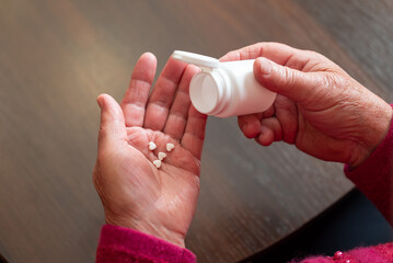 Senior woman pours heart-shaped pills from bottle. Elderly woman pouring heart-shaped pills from...