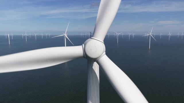 Offshore wind turbine fixed foundation, rotor, blades. Aerial drone video. Clean energy, renewable resource, wind power, wind farm.