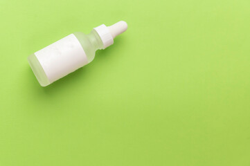 Transparent liquid product in glass bottle with dropper on green background, Natural cosmetics...