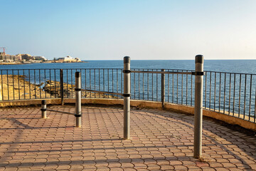 Set of metal poles with horizontal bars of different heights on a seaside promenade. Outdoor functional workout zone with ocean view, used for balance, jumping, or bodyweight exercises.