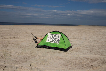 
Naked man in gas mask standing on a deserted beach, holding signs.