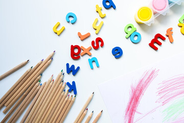 Colorful alphabet letters and colored pencils on white background