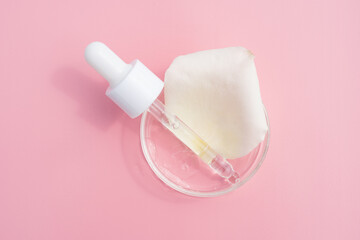 Cosmetic pipette with serum in petri dish on pink background. Face oil pipette dropper. Beauty...