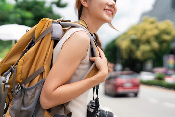 Travel. Young woman with backpack smiling on busy city street.