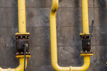 Two yellow industrial pipes with valves are mounted on a gray wall, showcasing a functional design...