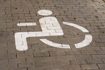 A clear wheelchair access symbol is prominently painted on the pavement in an urban setting,...
