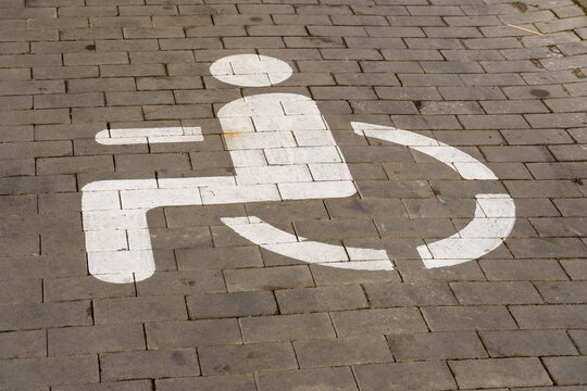 A clear wheelchair access symbol is prominently painted on the pavement in an urban setting, emphasizing the importance of accessibility for all