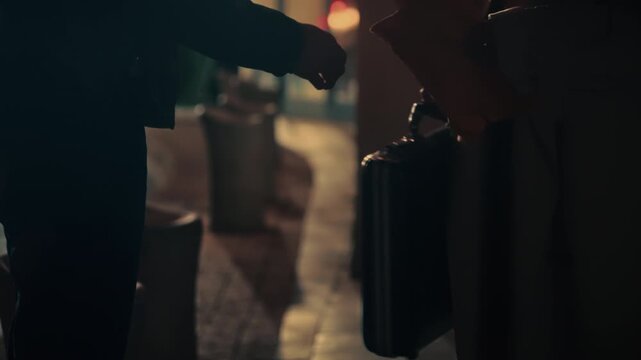 Briefcase exchange between two people in low light. Suspenseful, covert transaction perfect for spy thriller, crime drama, espionage, secret deal, or noir-style footage. undercover agents work.