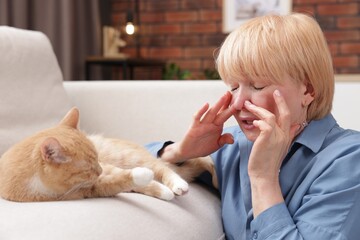 Senior woman suffering from allergy with her cat at home