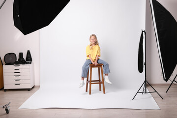 Little girl on white background in photo studio with professional equipment
