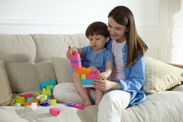 Mother and son playing with building bricks on sofa at home