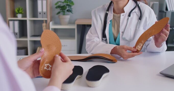 Orthopedists hands holding leather orthotic insole for orthopedic shoes of patient on medical examination in office. Doctor sitting at table with individual orthopaedic inset. Flatfoot support concept