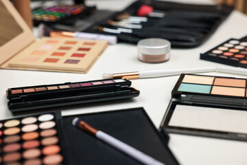 Different makeup products and brushes on dressing table, closeup