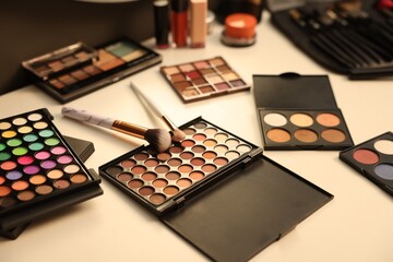 Different makeup products and brushes on dressing table, above view