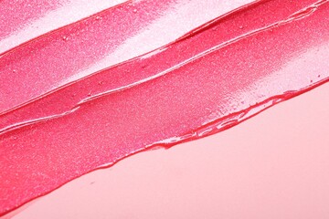 Sample of lip gloss on pink background, top view. Space for text