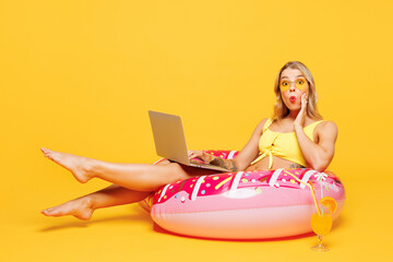 Full body young impressed fun woman wear bikini swimsuit rest near hotel pool lies on rubber ring...