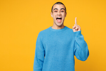 Young smart happy proactive middle eastern man wearing blue sweatshirt casual clothes holding index finger up with great new idea isolated on plain yellow orange background studio. Lifestyle concept.