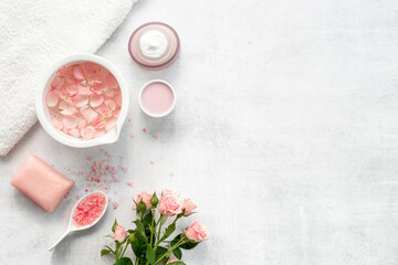 Homemade organic cosmetic with roses essential oil. Face cream with flowers and petals, top view
