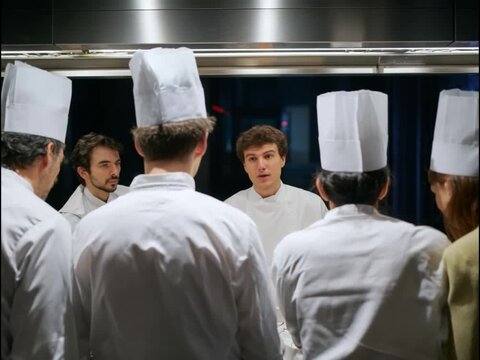 Chef Instructing Culinary Team: A chef passionately instructs his culinary team in a professional kitchen setting. The image captures the intense focus and collaboration within a high-end restaurant.
