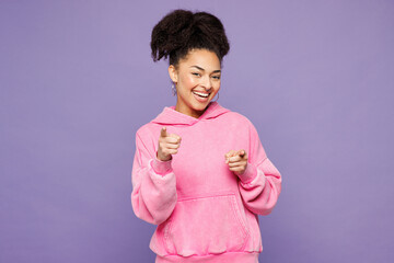 Young fun woman of African American ethnicity wear pink hoodie casual clothes point index finger camera on you motivating encourage isolated on plain pastel light purple background. Lifestyle concept.